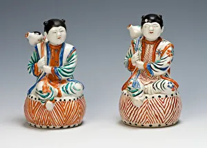 7279517 A pair of Kakiemon figures of karako each shown casually seated upon a drum, Edo Period, late 17th century (porcelain) by Japanese School, (17th century); height: 14.4 cm; Burghley House Collection, Lincolnshire, UK; (add.info.: CER0300 A pair of Kakiemon figures of karako each shown casually seated upon a drum, both hands holding tasselled cords attached to a double gourd bottle slung over their right shoulders, decorated in a Kakiemon palette, the flat bases impressed with gauze marks (one with restored crack around neck, chip to gourd), Edo Period, late 17th Century, 14.4cm high.); Burghley House A pair of Kakiemon figures of karako each shown casually seated upon a drum, Edo Period, late 17th century (porcelain)