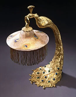 A table lamp with the base cast as a peacock holding the glass shade from its mouth, c