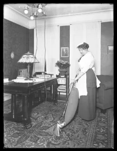 Unidentified woman demonstrating the use of the Apex vacuum cleaner, c Unidentified woman demonstrating the use of the Apex vacuum cleaner, c