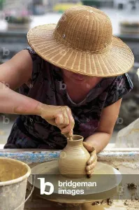 Woman modeling pot on wheel during Feast of Bread in Broc, Puy-de-Dome, France Woman modeling pot on wheel during Feast of Bread in Broc, Puy-de-Dome, France