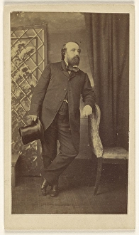Full-bearded man holding top hat standing leaning Full-bearded man holding top hat standing leaning