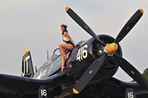 1940s style Navy pin-up girl sitting on a vintage Corsair fighter plane 1940s style Navy pin-up girl sitting on a vintage Corsair fighter plane