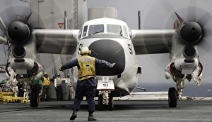 An aircraft director guides a C-2A Greyhound aircraft across the flight deck An aircraft director guides a C-2A Greyhound aircraft across the flight deck