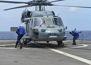 Airmen remove the chocks and chains from an MH-60S Sea Hawk Airmen remove the chocks and chains from an MH-60S Sea Hawk