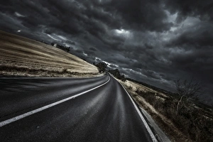 An asphalt road with stormy sky above, Tuscany, Italy An asphalt road with stormy sky above, Tuscany, Italy