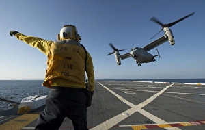 Aviation Boatswains Mate directs an MV-22 Osprey as it launches from the flight deck Aviation Boatswains Mate directs an MV-22 Osprey as it launches from the flight deck