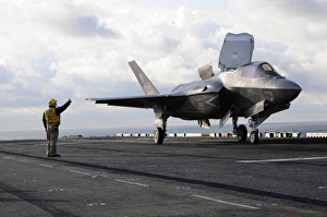 Aviation Boatswains Mate signals the pilot to lift an F-35B Lightning II off the Aviation Boatswains Mate signals the pilot to lift an F-35B Lightning II off the