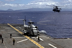 A CH-53D Sea Stallion sits on the flight deck as another prepares to land aboard A CH-53D Sea Stallion sits on the flight deck as another prepares to land aboard