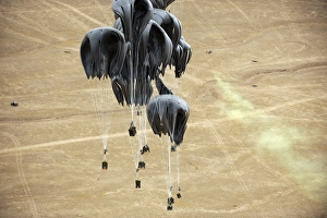 Container delivery system bundles parachute down to a drop zone marked by warfighters Container delivery system bundles parachute down to a drop zone marked by warfighters