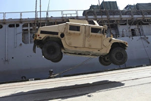 A crane lifts an M998 Humvee on the flight deck of USS Carter Hall A crane lifts an M998 Humvee on the flight deck of USS Carter Hall