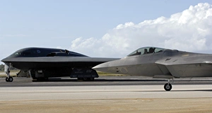 An F-22 Raptor taxis while a B-2 Spirit waits for clearance An F-22 Raptor taxis while a B-2 Spirit waits for clearance
