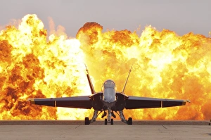An F/A-18 Hornet sits on the flight line as a wall of fire detonates behind it An F/A-18 Hornet sits on the flight line as a wall of fire detonates behind it