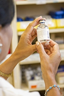 A female pharmacist examining a vial in a pharmacy A female pharmacist examining a vial in a pharmacy