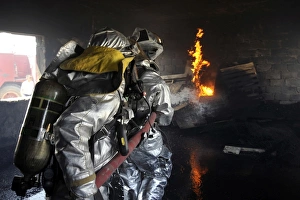 Firefighters extinguish a fire in a training room during live burn training Firefighters extinguish a fire in a training room during live burn training