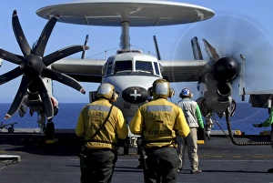 Flight deck directors watch as pilots of an E-2C Hawkeye start-up their engines Flight deck directors watch as pilots of an E-2C Hawkeye start-up their engines