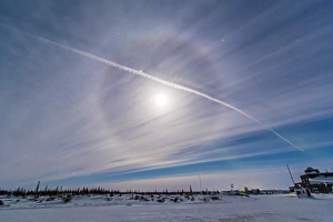 An ice crystal lunar halo around the gibbous moon with an aircraft jet contrail An ice crystal lunar halo around the gibbous moon with an aircraft jet contrail