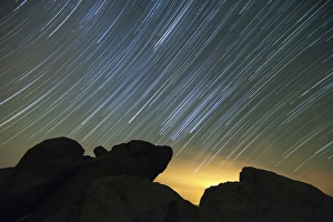 Light pollution illuminates the sky and star tails above large boulders Light pollution illuminates the sky and star tails above large boulders