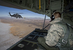 A loadmaster on an HC-130 watches as an HH-60G Pave Hawk refuels A loadmaster on an HC-130 watches as an HH-60G Pave Hawk refuels