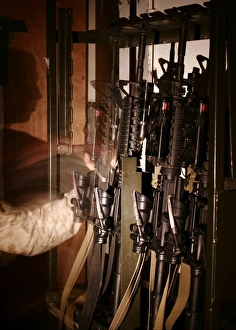 A Marine pulls an M-4 rifle off of the weapons rack A Marine pulls an M-4 rifle off of the weapons rack