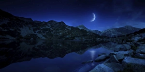 Moon rising over tranquil lake and mountains in Pirin National Park, Bulgaria Moon rising over tranquil lake and mountains in Pirin National Park, Bulgaria