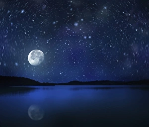 Moon rising over tranquil lake against starry sky Moon rising over tranquil lake against starry sky