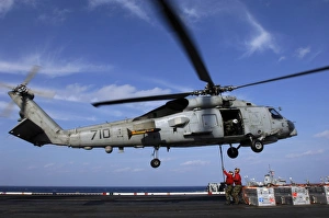 Ordnancemen connect transport cables to a SH-60B helicopter Ordnancemen connect transport cables to a SH-60B helicopter