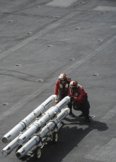 Ordnancemen push ordnance across the flight deck of USS Nimitz Ordnancemen push ordnance across the flight deck of USS Nimitz