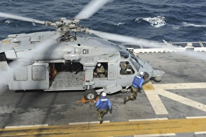 Personnel remove chock and chains from an H-60 Sea Hawk helicopter Personnel remove chock and chains from an H-60 Sea Hawk helicopter