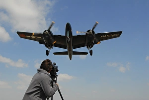 Photographer taking a picture of a F7F Tigercat flying overhead Photographer taking a picture of a F7F Tigercat flying overhead