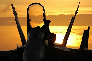 A plane captain enjoys a sunset from atop an F/A-18 Hornet A plane captain enjoys a sunset from atop an F/A-18 Hornet