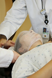 Radiation therapists fit a short face mask to a patient during radiation therapy Radiation therapists fit a short face mask to a patient during radiation therapy