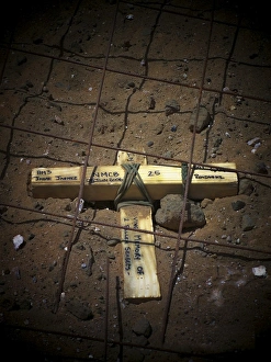 A road repair crew places a cross inside a road crater A road repair crew places a cross inside a road crater
