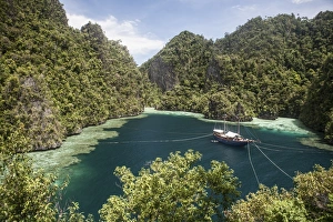 Rugged limestone islands frame an Indonesian pinisi schooner Rugged limestone islands frame an Indonesian pinisi schooner