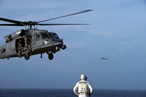 Sailor watches an Air Force HH-60G Pave Hawk helicopter prepare to land Sailor watches an Air Force HH-60G Pave Hawk helicopter prepare to land