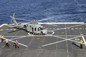 Sailors move in to chock and chain an MH-60S Sea Hawk helicopter Sailors move in to chock and chain an MH-60S Sea Hawk helicopter
