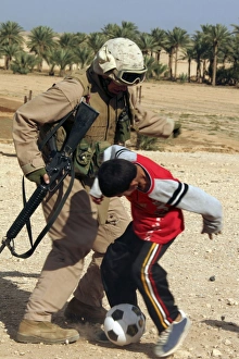 A soldier plays soccer with an Iraqi boy A soldier plays soccer with an Iraqi boy