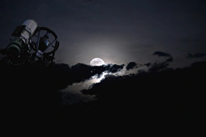 Telescope pointed out to the night sky with moon and clouds Telescope pointed out to the night sky with moon and clouds