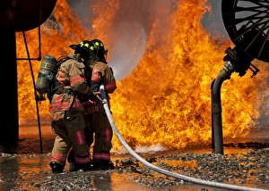 A two-man team battles a blaze at the front of a mock aircraft A two-man team battles a blaze at the front of a mock aircraft