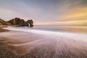 Durdle Door rock arch with beach in foreground, in evening light. Dorset, England, UK Durdle Door rock arch with beach in foreground, in evening light. Dorset, England, UK