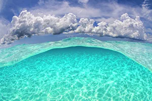 Light patterns on the seabed and fluffy cumulus clouds in the sky in a split level image Light patterns on the seabed and fluffy cumulus clouds in the sky in a split level image