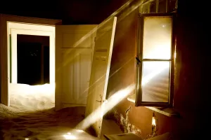 Light streaming through window on sand covered house in Kolmanskop Ghost Town, an Light streaming through window on sand covered house in Kolmanskop Ghost Town, an