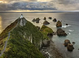 Images Dated 1st October 2006: RF- Nugget Point (Ka Tokata) lighthouse at sunrise, rain clouds sweeping in from the horizon