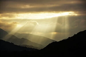 Shaft Gallery: Shafts of light at dusk over Wrynose pass and the Coniston hills from Ambleside, Lake District