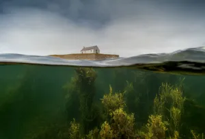 Split level image of the tiny chapel of St Cwyfan, surrounded by sea at high tide Split level image of the tiny chapel of St Cwyfan, surrounded by sea at high tide