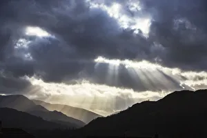 Sun rays shining through clouds onto Loughrigg Fell and hills of the Lake District Sun rays shining through clouds onto Loughrigg Fell and hills of the Lake District