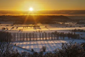 Winter sunset over the Somerset Levels from Walton Hill on a misty evening with snow on the ground Winter sunset over the Somerset Levels from Walton Hill on a misty evening with snow on the ground