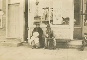 Photograph of a man and woman sitting outside of a storefront, early 20th century Photograph of a man and woman sitting outside of a storefront, early 20th century