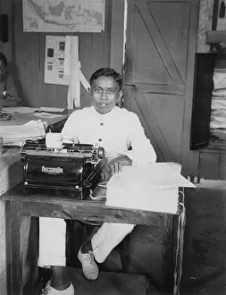 A young man sitting at a typewriter, Indonesia, 20th century A young man sitting at a typewriter, Indonesia, 20th century