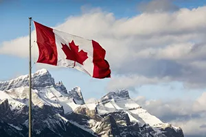 Canadian Flag Blowing In The Wind On A Flag Pole With Snow Covered Mountain Range In The Background With Blue Sky And Canadian Flag Blowing In The Wind On A Flag Pole With Snow Covered Mountain Range In The Background With Blue Sky And