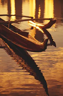 Closeup Of Koa Outrigger Canoe On Water With Reflection Of Golden Sunset Closeup Of Koa Outrigger Canoe On Water With Reflection Of Golden Sunset